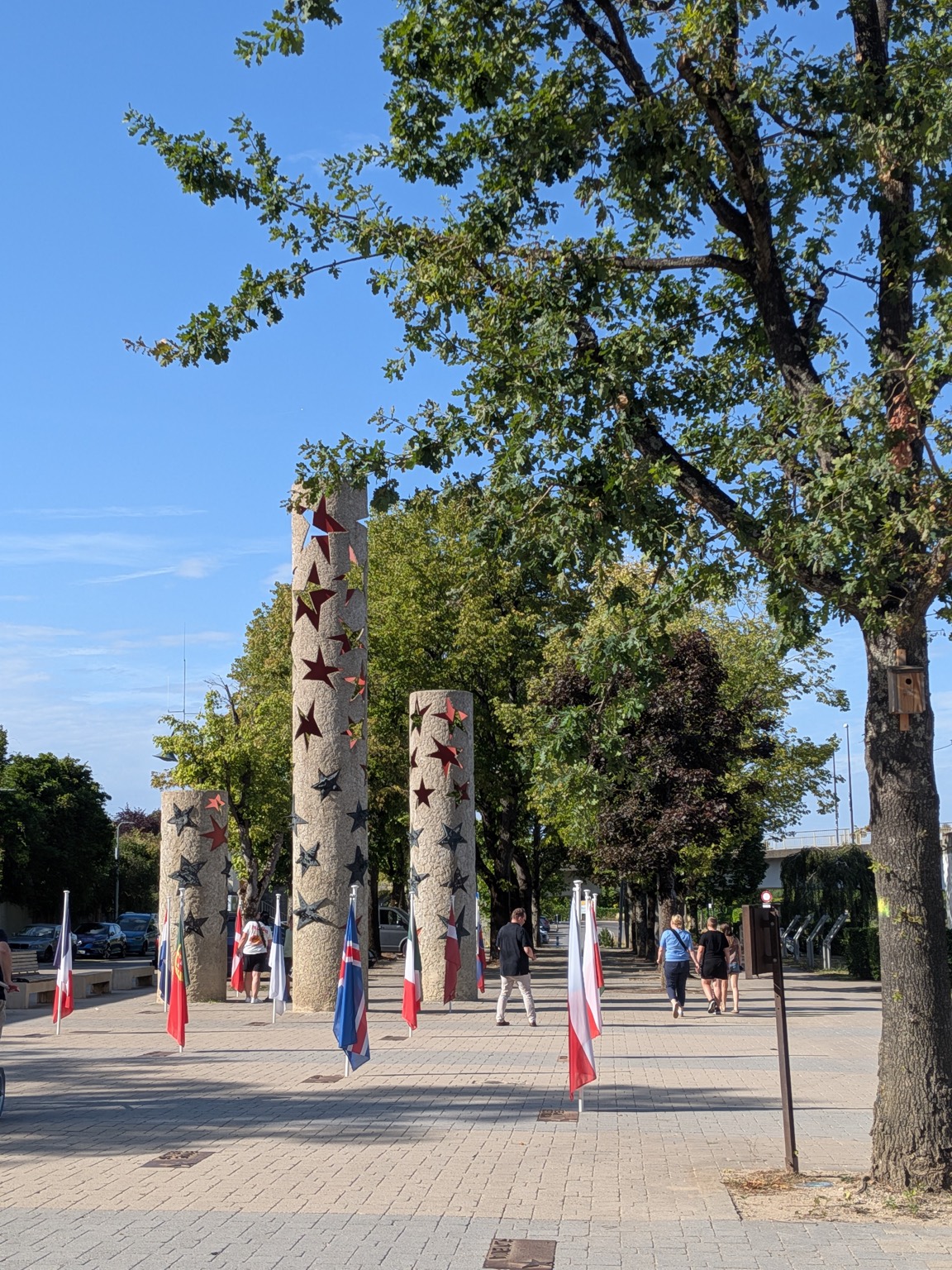 The Pillars of Nations monument in Schengen, star-decorated stone columns with national flags of Schengen member countries planted at their base
