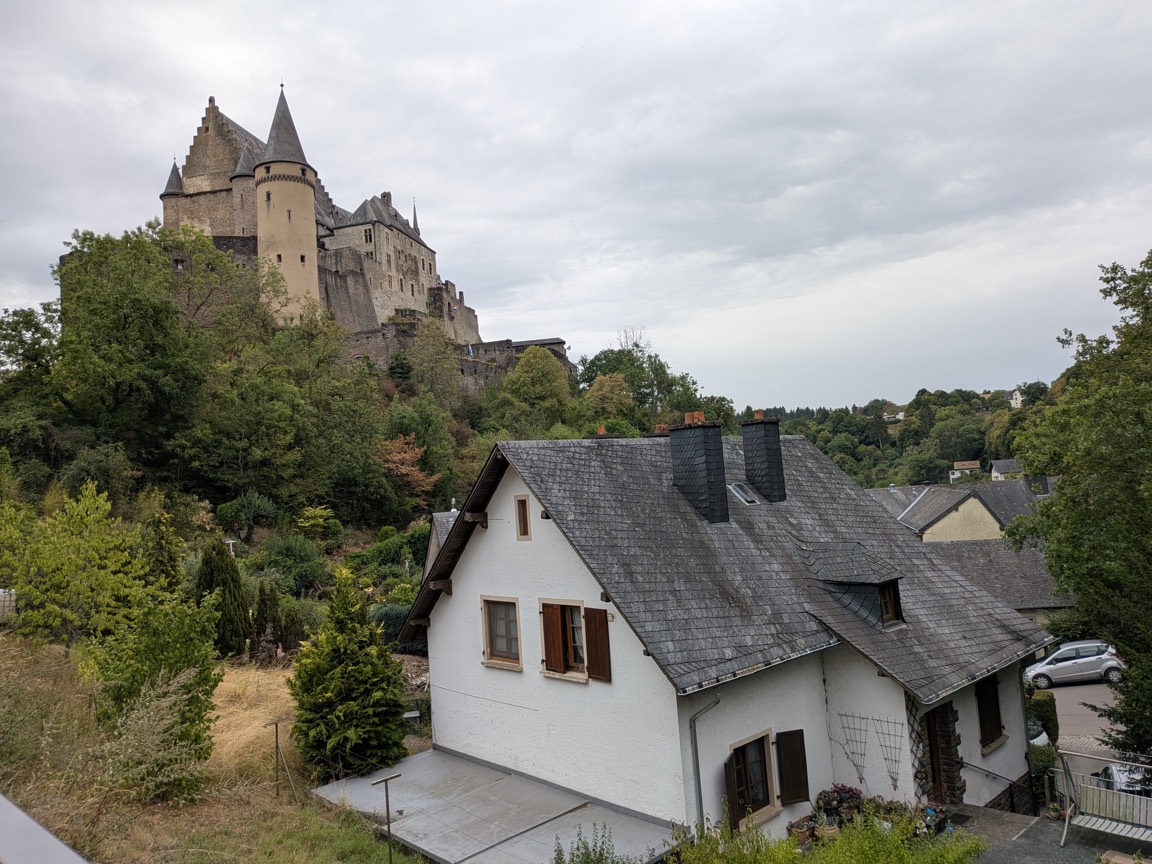 Vianden Castle in Luxembourg, a restored medieval fortress on a hilltop above the village, seen from a nearby rooftop