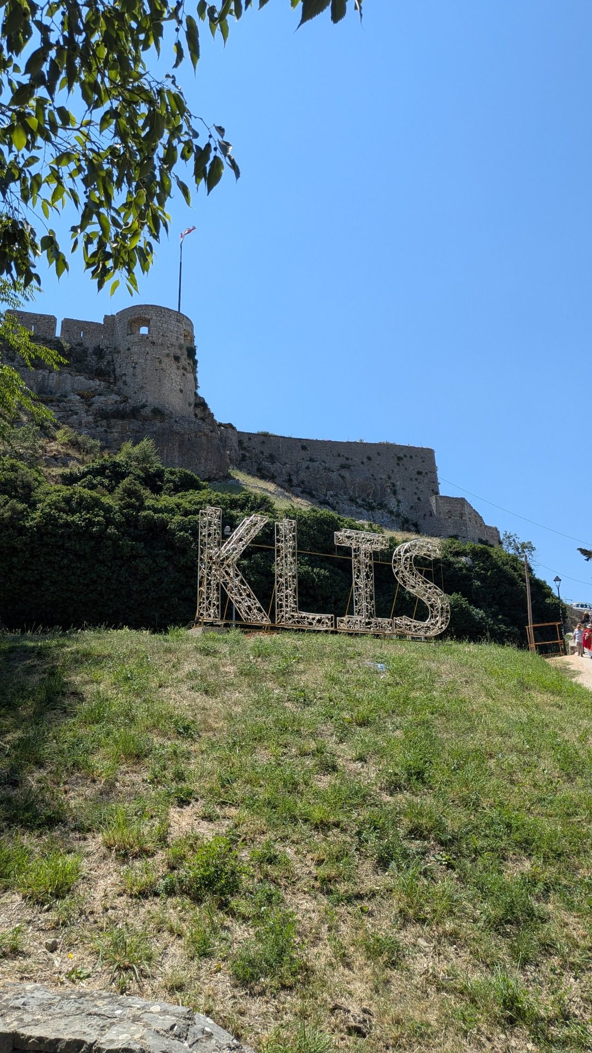 Klis Fortress above Split with the large Klis sign on the hillside under a clear blue sky